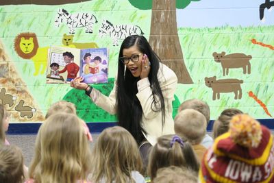 Thuba reading her book to children in a classroom