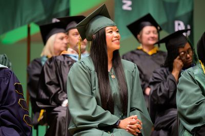 Thuba attending her college graduation, wearing her graduation robes with other students